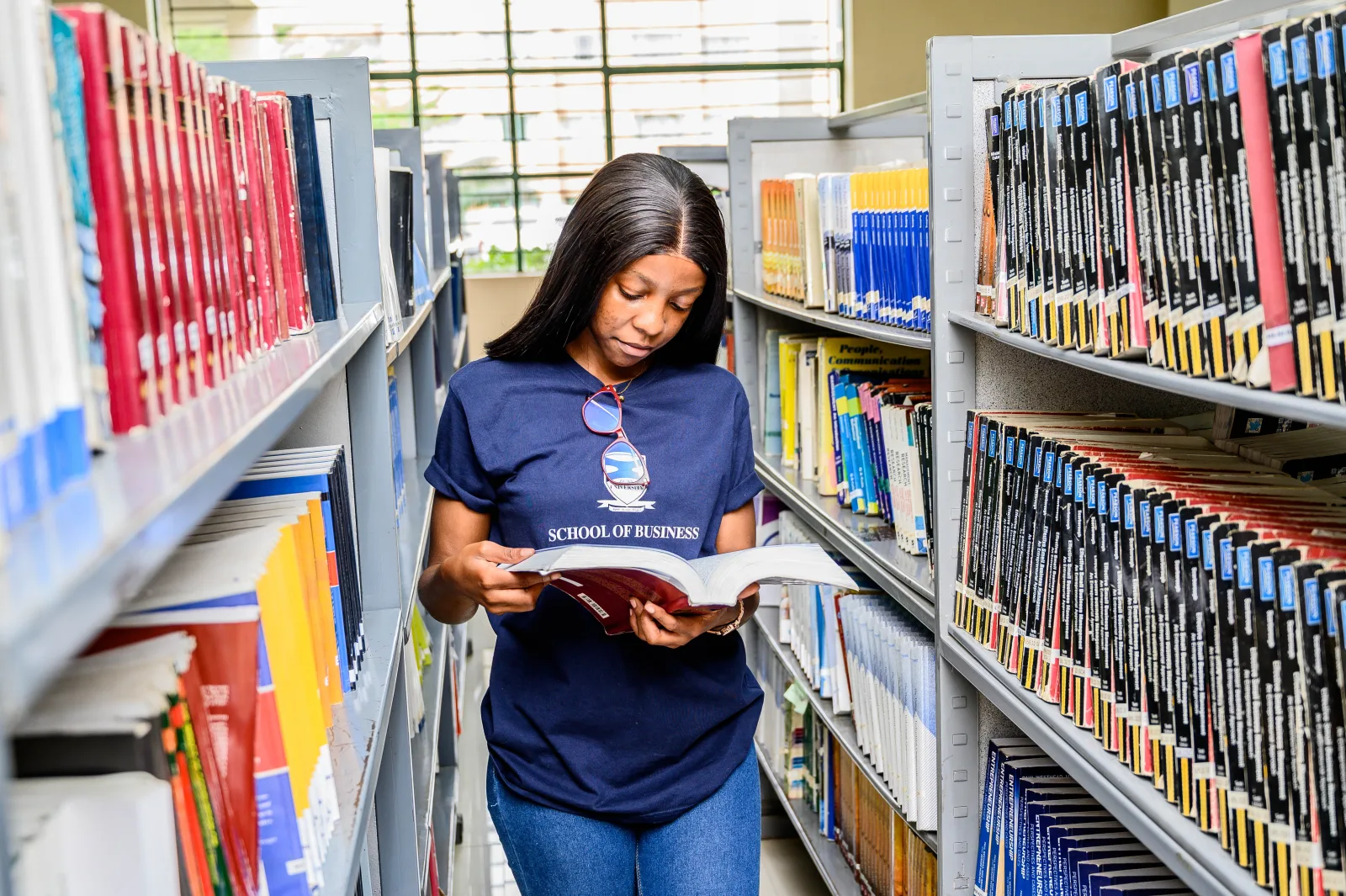 Student reading between the ZCAS/ZCASU Library shelves